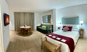 een hotelkamer met een groot bed en een groene bank bij Apartamentos Turísticos La Plaza in Chipiona