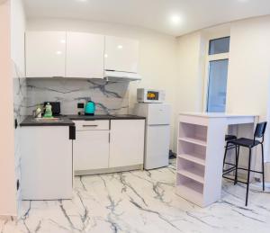 een keuken met witte kasten en een marmeren vloer bij Панорамные Апартаменты в новом доме in Kiev