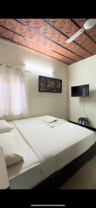 - un grand lit blanc dans une chambre avec plafond dans l'établissement Sai, à Ambātturai