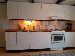 a kitchen with white cabinets and a sink and a stove at Villa Vi apartment 2 in Vimmerby