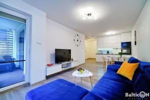 a living room with a blue couch and a table at Apartamenty BalticON Polanki Park in Kołobrzeg