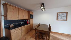 une cuisine avec des placards en bois et une table avec des chaises dans l'établissement Tignes2100 - Le Télémark, à Tignes