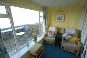 a living room with two chairs and a balcony at 3 The Promenade in Sheringham