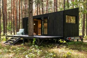 une petite maison noire dans les bois avec un arbre dans l'établissement Bento Two, 