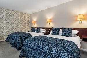 a hotel room with two beds with blue and white sheets at Mariners Hotel in Haverfordwest