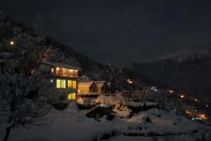 uma casa com luzes acesas na neve à noite em Homestay Nature Auli em Jyotirmath