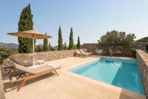 eine Villa mit einem Pool und einem Sonnenschirm in der Unterkunft Phāea Blue Palace in Elounda