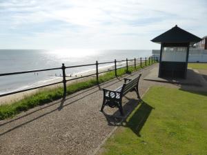 a park bench next to a fence and the beach at 35 Siesta Mar in Mundesley +7 photos