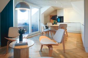 a living room with chairs and a table and a kitchen at STAY Penthouse in Kolding