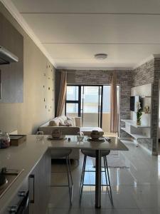 a kitchen with a table and a living room at Classy 2 bedroom in Halfway Gardens in Midrand
