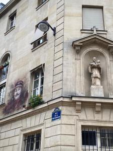 un bâtiment avec une statue sur son côté dans l'établissement Quatre rêves à Lutèce, à Paris
