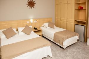 a hotel room with two beds and a desk at River Palace Hotel in Divinópolis