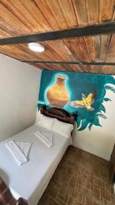 Zimmer mit einem Bett und einem Gemälde an der Wand in der Unterkunft Hostería El Sendero - Cocorná in Cocorná