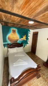 Bett in einem Zimmer mit Wandgemälde in der Unterkunft Hostería El Sendero - Cocorná in Cocorná