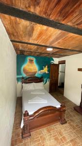 Schlafzimmer mit einem Bett mit Wandgemälde in der Unterkunft Hostería El Sendero - Cocorná in Cocorná
