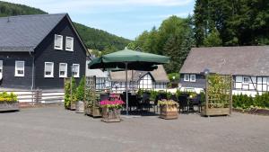 a table with an umbrella in front of a house at Gasthof Zwilling in Schmallenberg