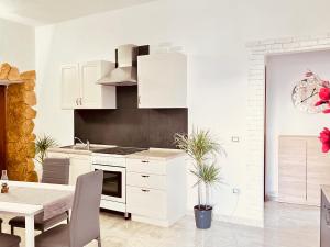 una cucina con armadi bianchi e un tavolo con una pianta in vaso di Newly renovated apartment in the heart of Sorso a Sorso