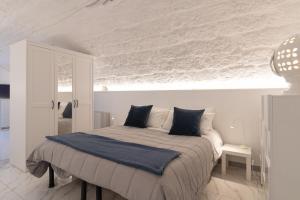 een witte slaapkamer met een bed met een blauwe deken bij La Porta Sul Mare in Mola di Bari