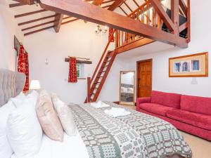 1 dormitorio con 1 cama y 1 sofá rojo en Majestic Farmhouse Barn 8 Guests Pass the Keys en Pudsey