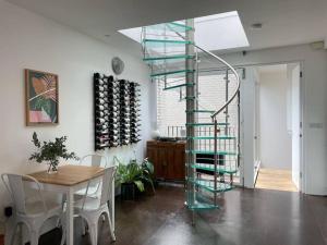 a glass spiral staircase in a dining room with a table at Stylish 3 Bed House, Shoreditch in London