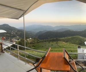 a bench on a balcony with a view of mountains at หลังสวน โฮมสเตย์ ดอยม่อนแจ่ม2 in Mon Jam
