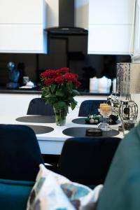une table avec un vase de fleurs rouges sur elle dans l'établissement Apartament Centrum Legnicy Janson, à Legnica