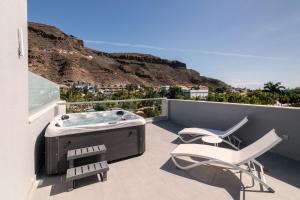 a hot tub and two chairs on a balcony with a mountain at Cordial Mogán Paraíso in Puerto de Mogán
