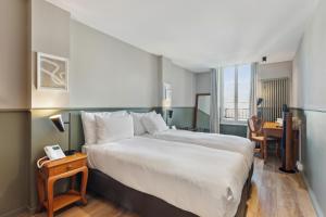 Schlafzimmer mit einem großen weißen Bett und einem Schreibtisch in der Unterkunft Hôtel de la Couronne in Morges