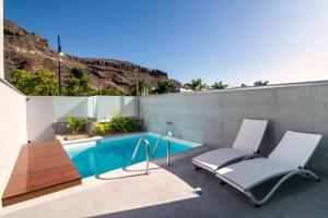 a patio with two chairs and a swimming pool at Apartamentos Cordial Mogán Paraíso in Puerto de Mogán