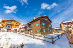 een blokhut in de sneeuw met een hek bij Chalet San Valentino - Happy Rentals in Livigno