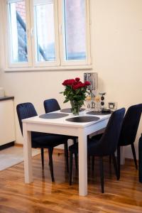 - une table à manger blanche avec un vase de roses dans l'établissement Apartament Centrum Legnicy Janson, à Legnica
