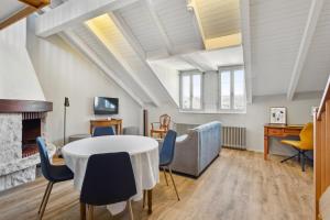 een woonkamer met een tafel en stoelen en een open haard bij Hôtel de la Couronne in Morges