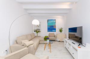 a white living room with a couch and a tv at Es Reco in Costitx