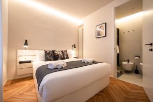 1 Schlafzimmer mit einem großen weißen Bett und einem Badezimmer in der Unterkunft Verona Liberty Flats - Torricelle e Adige in Verona