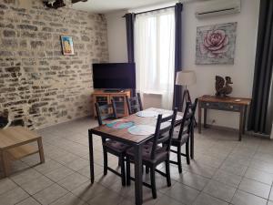 una sala da pranzo con tavolo, sedie e TV di Souvenirs d'hier a Hyères