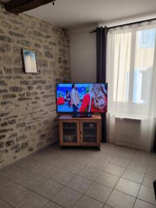 un salon avec une télévision à écran plat sur une table dans l'établissement Souvenirs d'hier, à Hyères