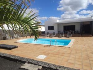 einen Pool mit Stühlen und ein Gebäude in der Unterkunft Casa Airalba in Tías