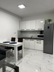 a white kitchen with a table and a refrigerator at Cozy place in Baia Mare