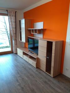 Gasthof Pension Hetzenbichl في سانكت يوهان ايم بونغ: غرفة معيشة مع جدار برتقالي وتلفزيون