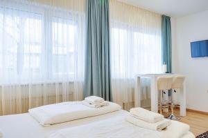 1 dormitorio con 2 camas, mesa y ventana en Wohnen auf Zeit - Studiowohnung Innsbruck en Innsbruck