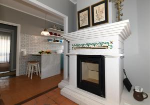 a white fireplace in a living room with a kitchen at Casa do Adro, casaspensadas in Juncal