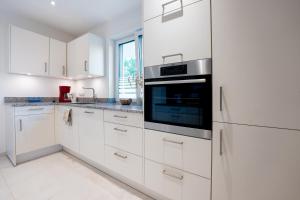 eine weiße Küche mit weißen Schränken und einer Mikrowelle in der Unterkunft Rosenbogen in Bad Wörishofen
