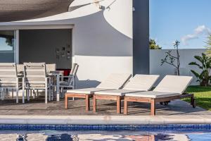 a group of white lounge chairs and a pool at Chill out of City 2 in Chiclana de la Frontera