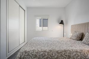 a white bedroom with a bed and a window at Chill out of City 2 in Chiclana de la Frontera +13 photos