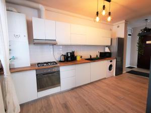 uma cozinha com armários brancos e um forno com placa de fogão em Serenity Suite em Sinaia