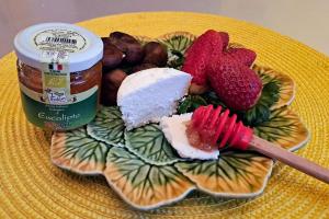 a plate of food with cheese and strawberries and a jar of jam at Oasi di Frattamaggiore in Frattamaggiore