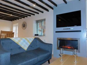 a living room with a blue couch and a fireplace at Anchor Cottage, Sheringham - Keys Holiday Cottages in Sheringham