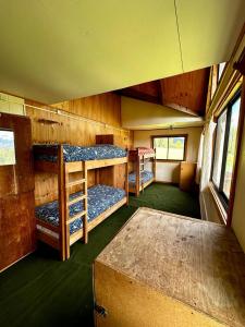 a room with three bunk beds and a table at Hostal Las Natalias in Futaleufú