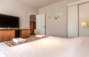 um quarto com uma grande cama branca e uma televisão de ecrã plano em Cozy Apartment Downtown Great Lake Views MF1 by Apartments Bariloche em San Carlos de Bariloche
