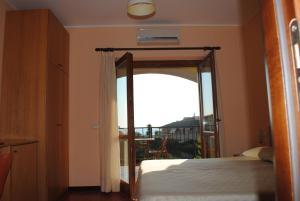 1 dormitorio con puerta abierta a un balcón en Larus Hotel, en Sangineto
